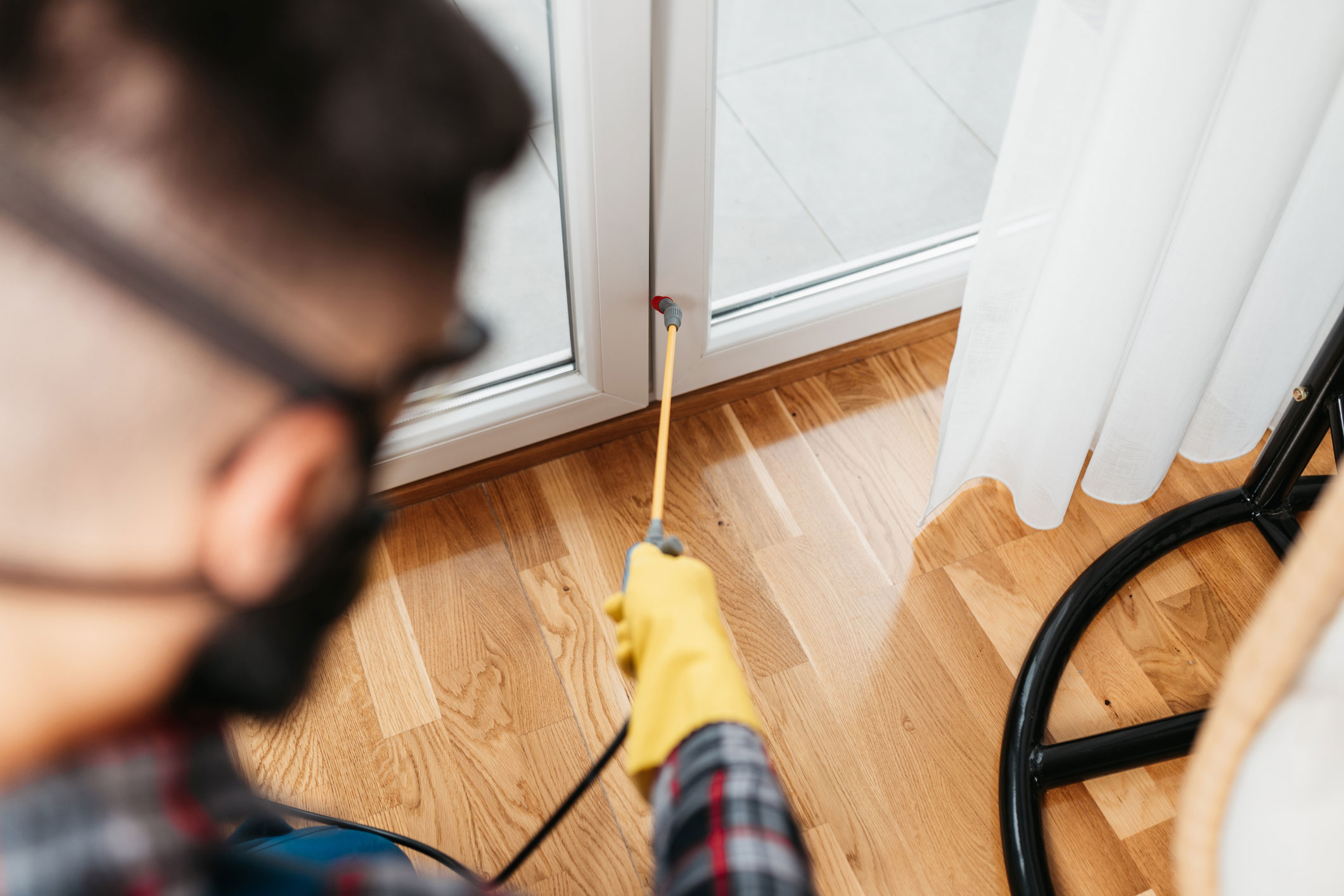 Pest control professional spraying the base of a door